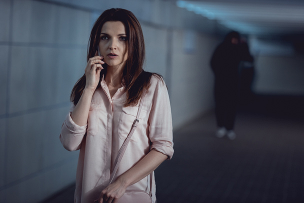 selective focus of woman talking on smartphone near thief in underpass - Zdjęcie, obraz