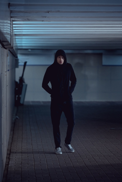 thief in black hoodie walking in underpass - 写真・画像
