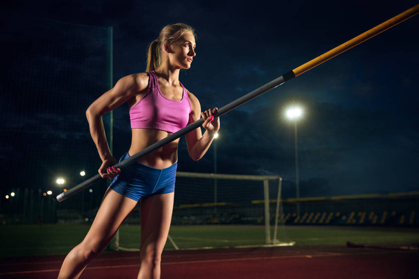 Female pole vaulter training at the stadium in the evening - Foto, afbeelding