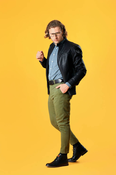 Стильний молодий чоловік у повсякденному одязі на кольоровому фоні
 - Фото, зображення