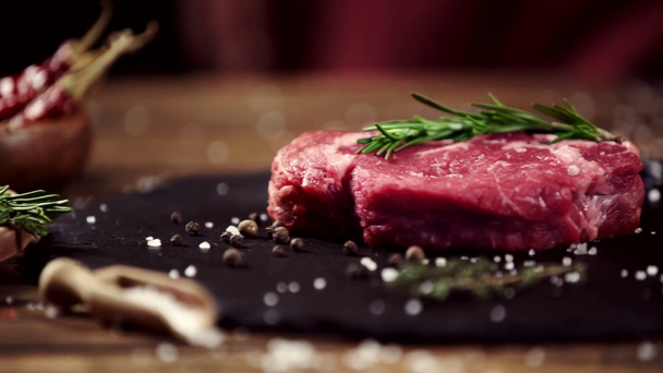 falling rosemary on raw meat steak on table with ingredients - Footage, Video