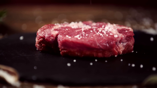 падение соли на стейк из сырого мяса на стол с ингредиентами
 - Кадры, видео