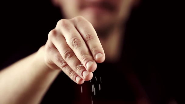 vista recortada del hombre condimento algo con sal aislada en negro
 - Metraje, vídeo