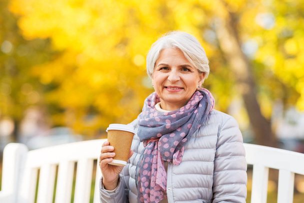 senior woman drinking coffee in autumn park - Fotoğraf, Görsel