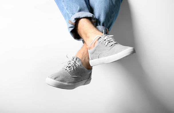 Πόδια του νεαρού άντρα με τζιν και κομψά παπούτσια σε λευκό φόντο - Φωτογραφία, εικόνα
