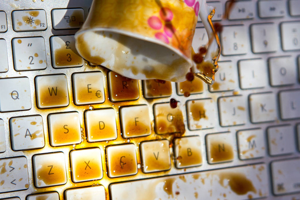 cup of coffee spilling onto a laptop keyboard - Zdjęcie, obraz