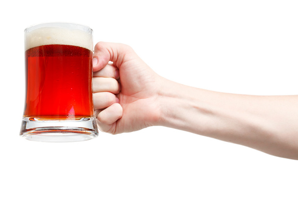 Closeup of a male hand holding up a glass of beer over a white b - Foto, immagini