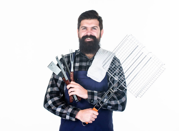 Roasting and grilling food. Man hold cooking utensils barbecue. Tools for roasting meat outdoors. Picnic and barbecue. Tips for cooking meat. Barbecue season. Bearded hipster wear apron for barbecue - Photo, Image
