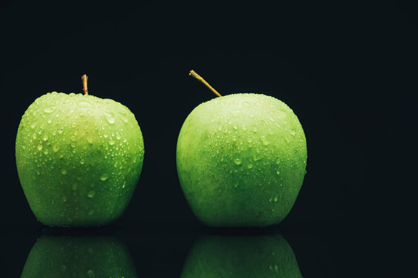 Duas maçãs verdes em um fundo de mesa de vidro preto
. - Foto, Imagem
