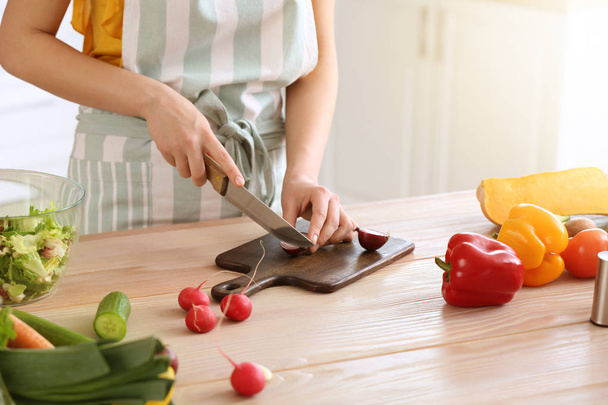 Beautiful woman preparing tasty vegetable salad in kitchen at home - Fotografie, Obrázek