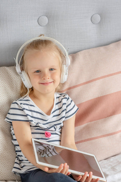 Caucasian Little Girl in Headphone Watching Tablet in Bed, Home Interior, Modern Device Technologies Scandinavian Style - Zdjęcie, obraz