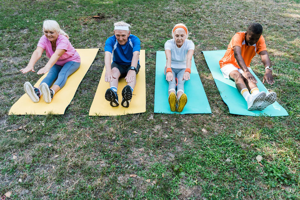 hombres y mujeres atléticos jubilados y multiculturales que ejercen sobre colchonetas de fitness
  - Foto, Imagen
