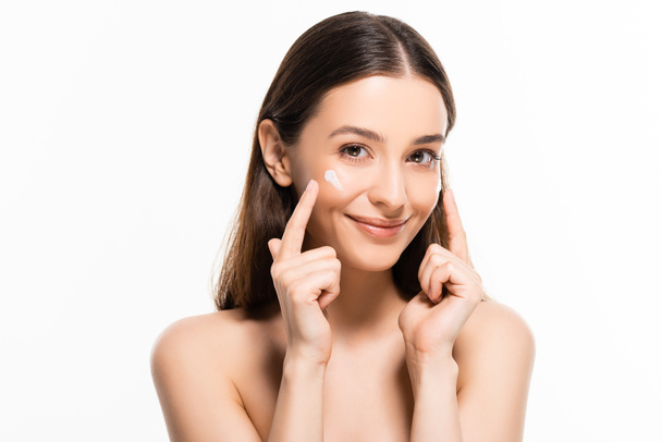 beautiful smiling naked woman with perfect skin pointing with fingers at cosmetic cream on face isolated on white - Photo, Image