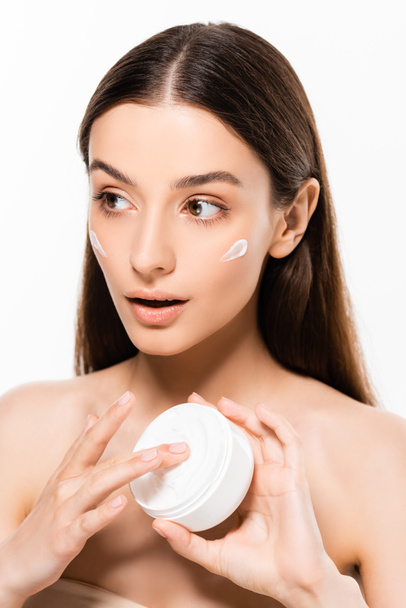 hermosa joven sorprendida mujer con la piel perfecta aplicación de crema cosmética aislada en blanco
 - Foto, Imagen