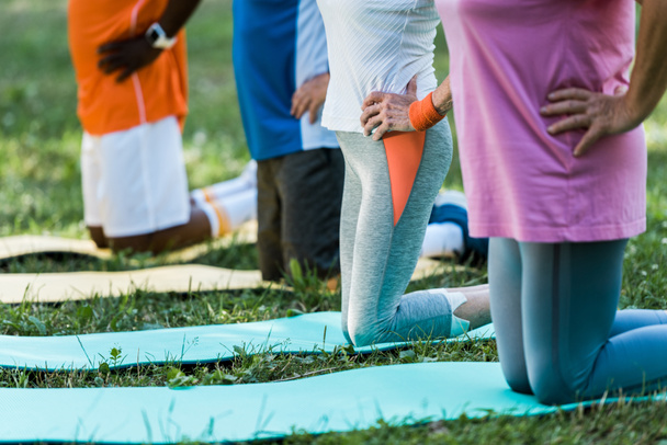 cropped view of multicultural pensioners with hand on hips exercising on fitness mats  - Fotografie, Obrázek
