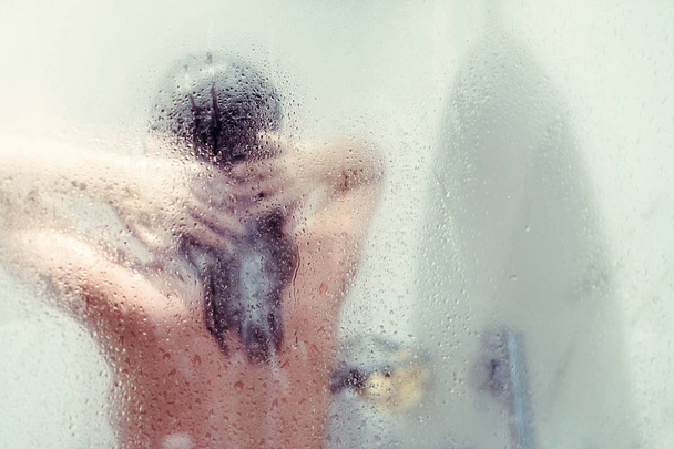 Sylwetka Naga piękna kobieta mycie włosów w prysznic za mokre szkło misted. - Zdjęcie, obraz