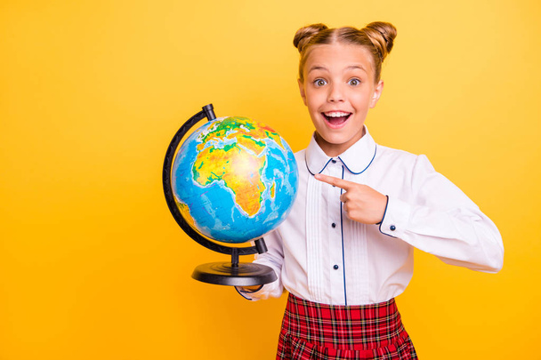 Portrait of her she nice attractive lovely cheerful cheery positive glad genius pre-teen girl in white shirt pointing at globe isolated over bright vivid shine yellow background - Foto, imagen