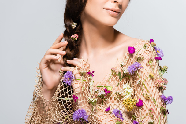 visão parcial da bela mulher tocando trança em malha com flores silvestres de primavera isoladas em cinza
 - Foto, Imagem