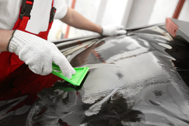 Male worker tinting car window outdoors - 写真・画像