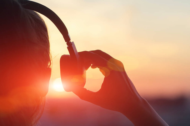 Girl in headphones listening to music in the city at sunset  - Foto, imagen