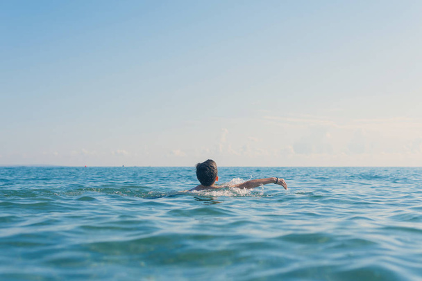 13 years old boy swimming and relaxation in the sea waves. Concept of family summer vacation - Photo, image