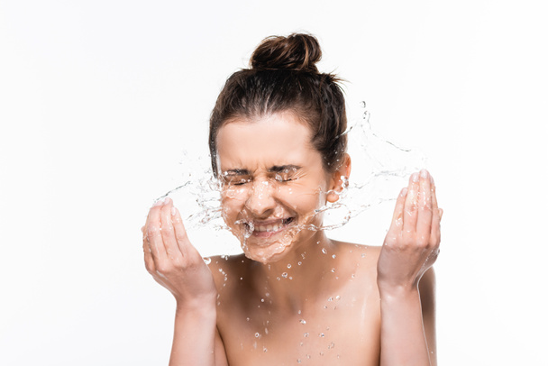 Gelukkig naakte jonge brunette vrouw met natuurlijke schoonheid wassen met schoon water splash geïsoleerd op wit - Foto, afbeelding