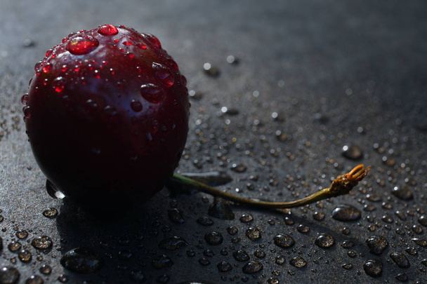 ciliegie succose rosse in gocce d'acqua su uno sfondo scuro
 - Foto, immagini