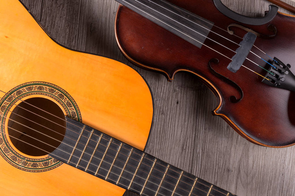 Klasyczne skrzypce i gitara na drewnianym tle. Tradycyjne instrumenty muzyczne - Zdjęcie, obraz