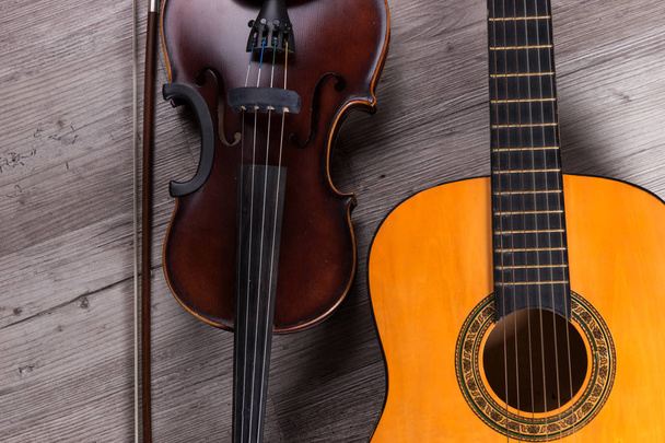 Klassieke viool en gitaar op houten achtergrond. Traditionele muziekinstrumenten - Foto, afbeelding