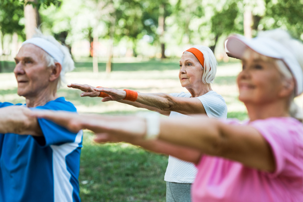 вибірковий фокус жінки у відставці, яка займається фізичними вправами біля пенсіонерів у парку
  - Фото, зображення