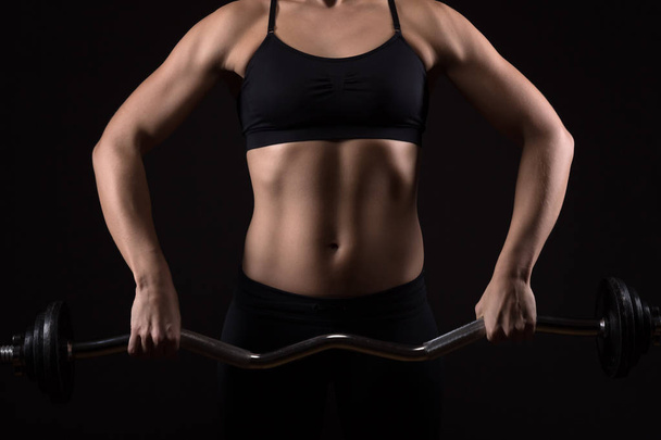 Frau mit perfekt trainiertem Körper trainiert auf einer Langhantel. fi - Foto, Bild