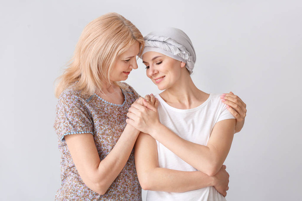 Γυναίκα μετά από χημειοθεραπεία με τη μητέρα της σε ανοιχτόχρωμο φόντο - Φωτογραφία, εικόνα