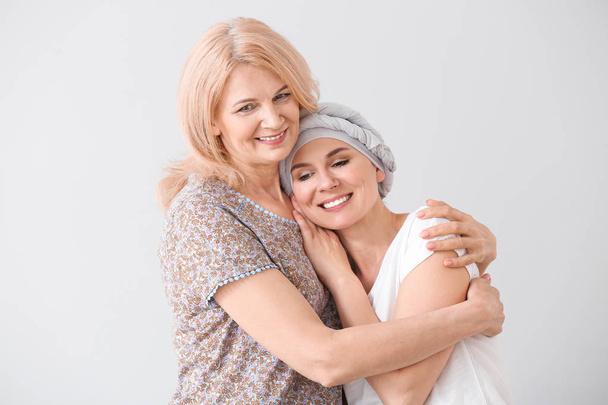Woman after chemotherapy with her mother on light background - Photo, Image