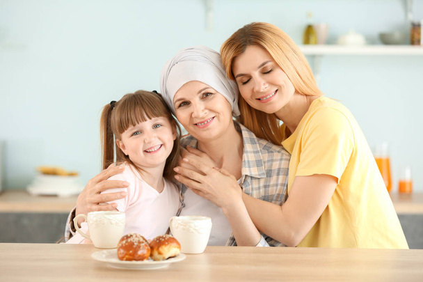 Mujer madura después de la quimioterapia con su familia en la cocina en casa
 - Foto, Imagen