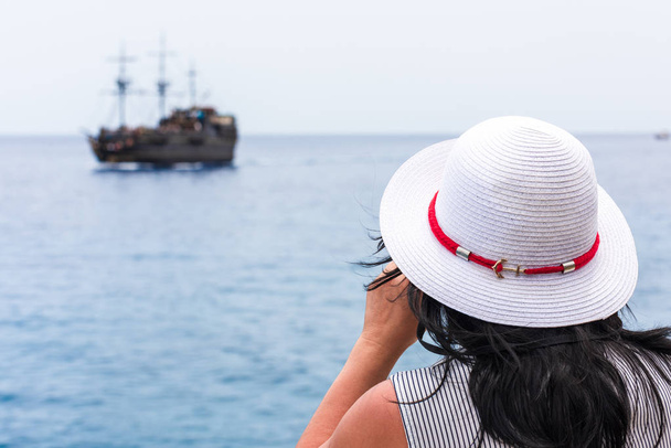Молода жінка дивиться човен з біноклями здалеку
 - Фото, зображення