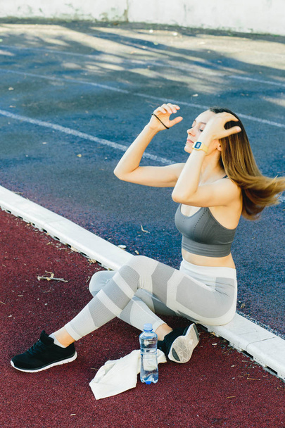 Mulher bonita sentada no chão com uma garrafa de água depois de Jogging ao ar livre
 - Foto, Imagem