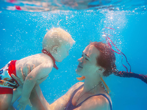 Krásná mladá žena (matka, Učitelka) s roztomilým chlapeckým chlapcem v motýlku, svým synem pod vodou v bazénu, se učí plavat. Koncepce sportu, rodiny, lásky a dovolené - Fotografie, Obrázek