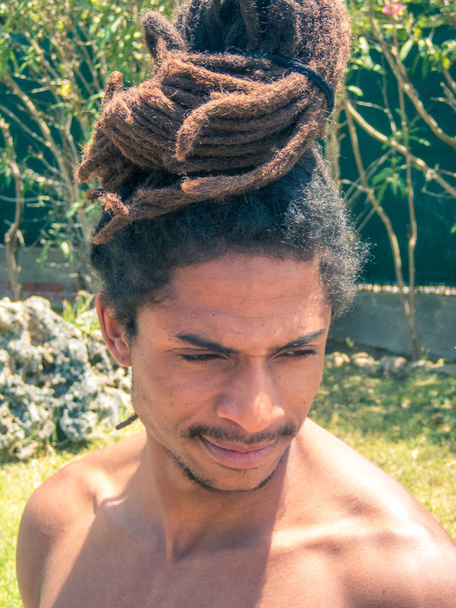 Черный мужчина с афроволосами и дредами, собранными на голове
. - Фото, изображение