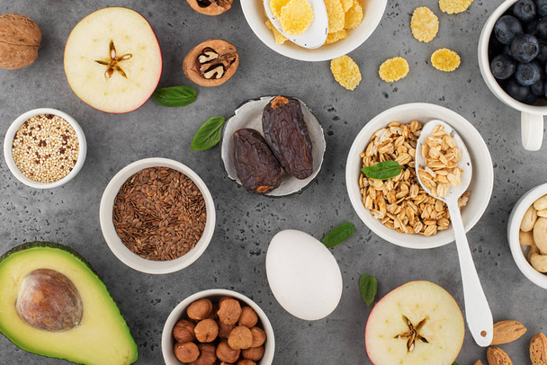 Ingredients for a healthy breakfast, nuts, oatmeal, flaxseed, dried fruit, avocado, egg, quinoa, cornflakes, berries, fruits, blueberry, almonds, walnuts. The concept of natural organic food in season - Foto, Imagem