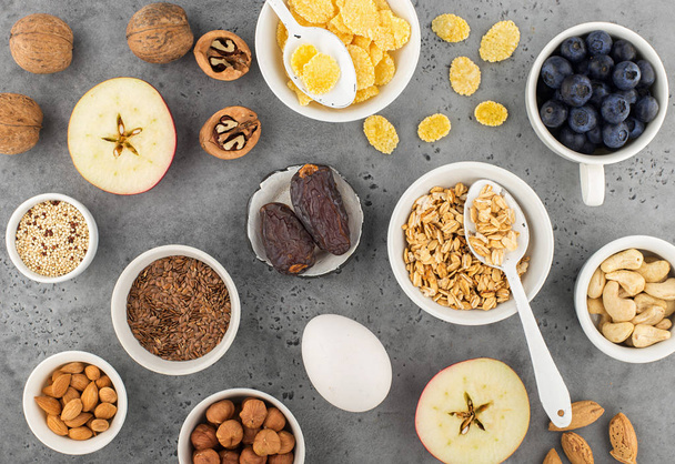 Ingredients for a healthy breakfast, nuts, oatmeal, flaxseed, dried fruit, avocado, egg, quinoa, cornflakes, berries, fruits, blueberry, almonds, walnuts. The concept of natural organic food in season - Photo, image