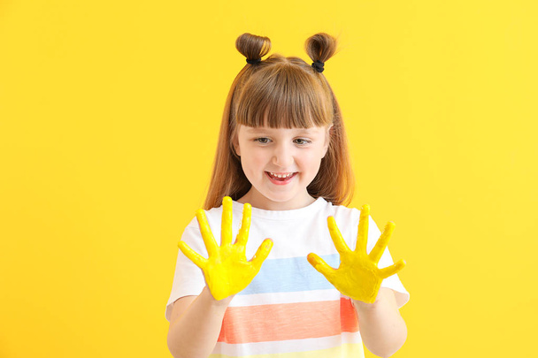 Schattig klein meisje met handen in verf op kleur achtergrond - Foto, afbeelding