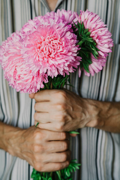 Man holds  bouquet of pink chrysanthemums - Foto, Imagen