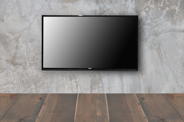 LCD телевізор на бетонній стіні з дерев'яною підлогою
 - Фото, зображення