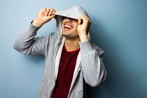 Happy young man laughing from under his hooded top - Foto, afbeelding