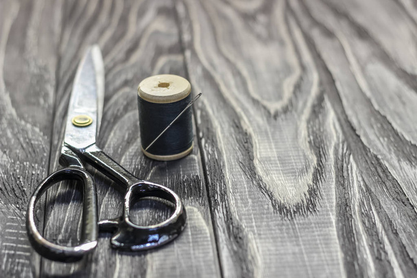 On a black wooden stench, close-up, scissors spool of thread wit - 写真・画像