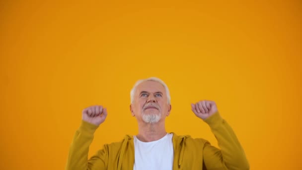 Extremely happy pensioner performing success dance, stretching hands up, winner - Materiał filmowy, wideo