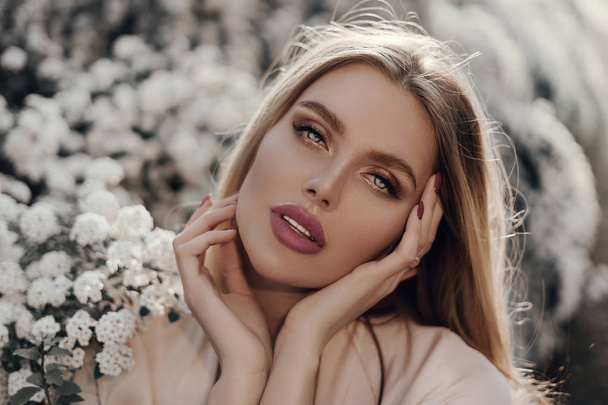 Portrait of a beautiful blonde girl in flowers - Photo, Image