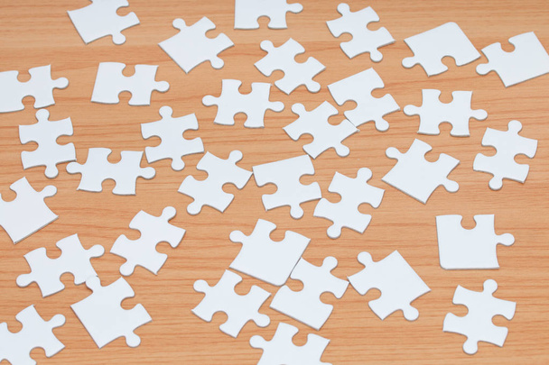 White jigsaw puzzle on wood table. - 写真・画像