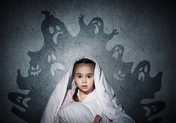 Scared girl with pillow hiding under blanket. Startled kid sitting in his bed at home. Little girl afraid of dark. Covered child not sleep at night. Fearful girl in pajamas and imaginary monsters. - Fotoğraf, Görsel