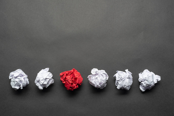 Pelota de papel rojo arrugado entre bolas blancas
 - Foto, Imagen